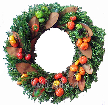 Fresh fall wreath adorned with vibrant pumpkins, adding a fiery touch of color and seasonal charm to door decor.