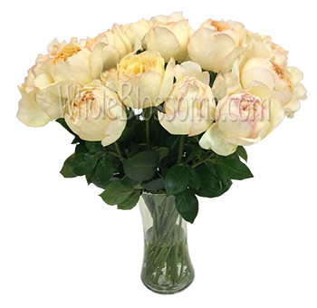 A vase of freshly cut Caramel Piaget Just Peachy Garden Roses with lush green leaves, ideal for wedding centerpieces or home décor.
