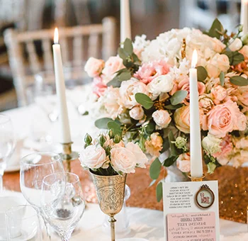 DIY wedding flowers featuring a romantic table centerpiece with blush roses, eucalyptus, candles, and elegant place settings for a personalized wedding look.