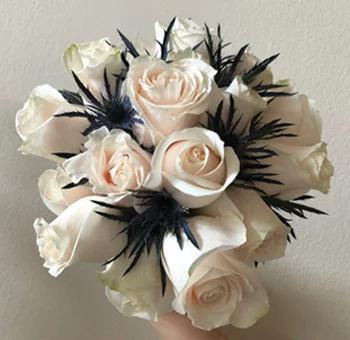 Cream rose wedding bouquet with dark thistle accents, part of bulk wedding flower packages for elegant floral designs.