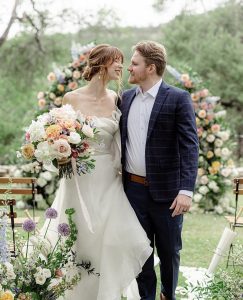 Newlywed couple with vintage wedding theme surrounded by flowers.