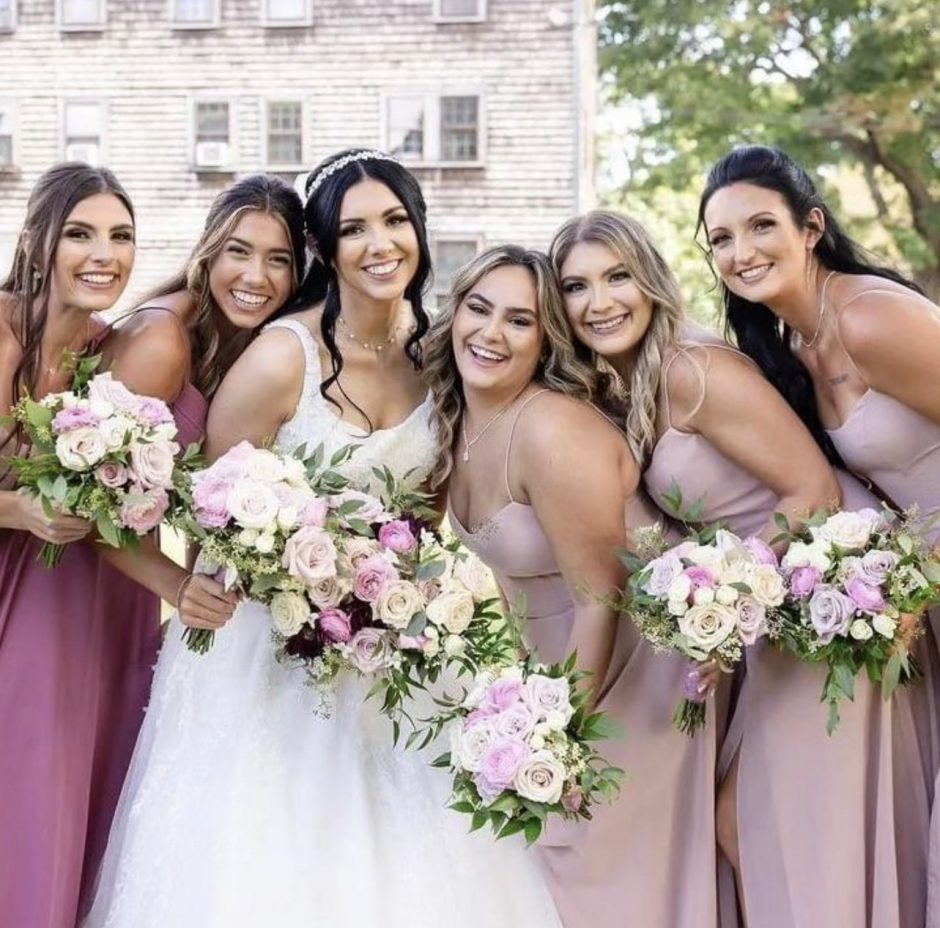 Bride and bridesmaids with bouquets with pink roses and burgundy flowers.