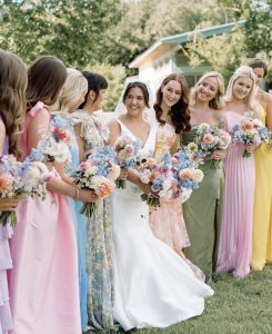Bride and bridesmaids with colorful dresses and pastel flowers.