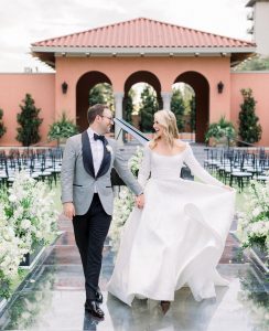 Couple walking into their fairy tale wedding with white flowers.