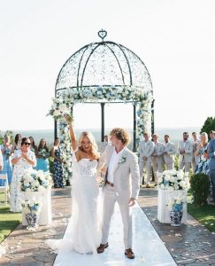 Newlywed couple with white and blue flower wedding theme.