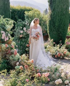 Bride holding bouquet of pink and cream ranunculus.