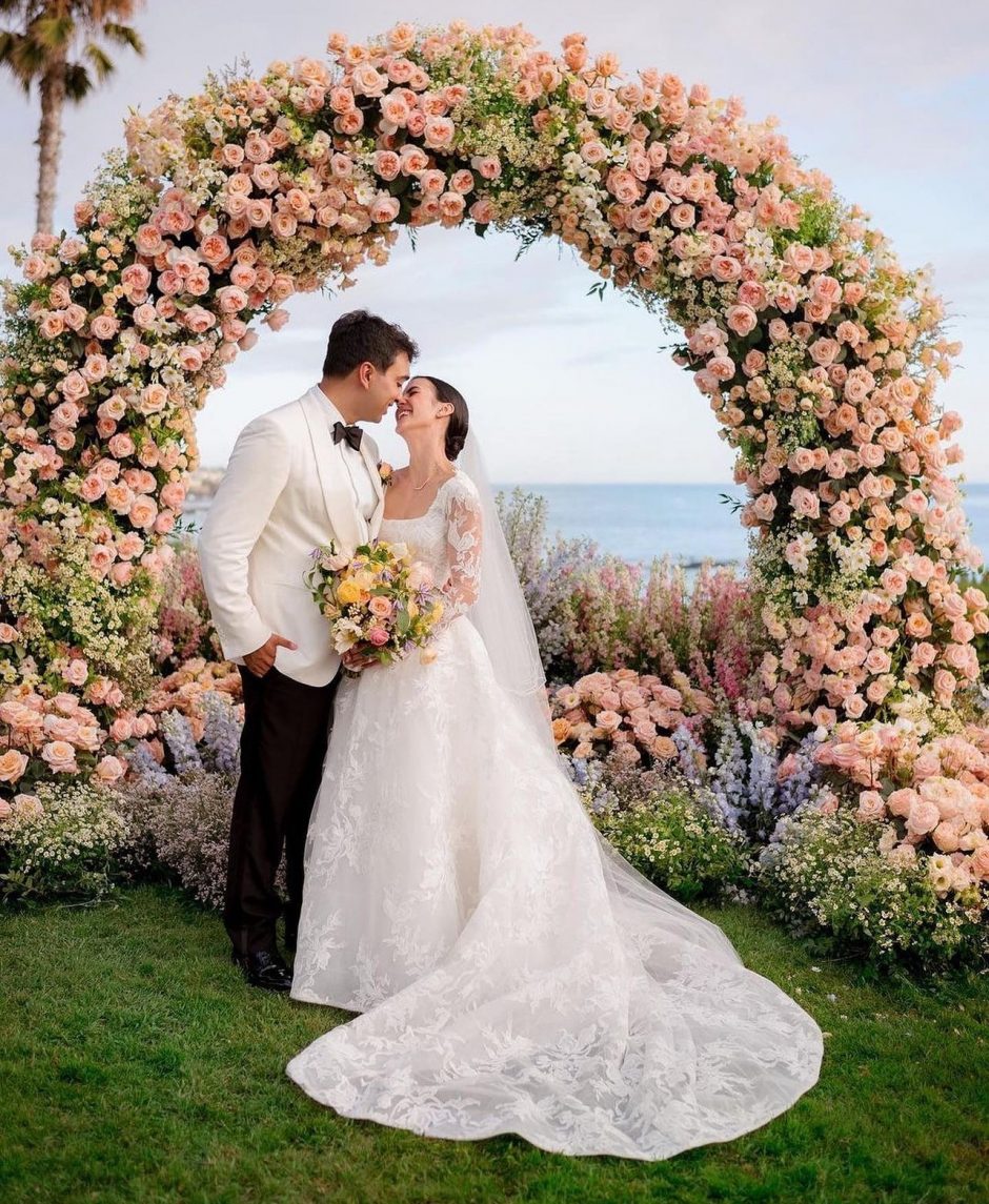 Newlywed couple by oceanside with colorful wedding flowers.