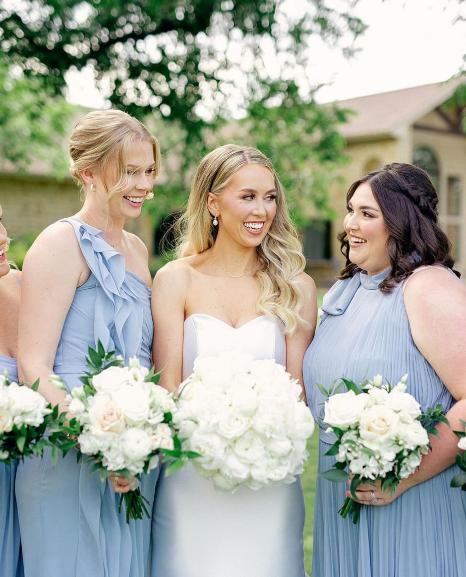 Bride and bridesmaids comparing their bouquets of white roses and white peonies.