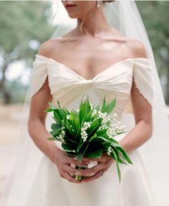 Bride holding wedding bouquet with lily of the valley.