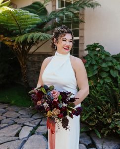 Bride holding wedding bouquet with burgundy flowers.