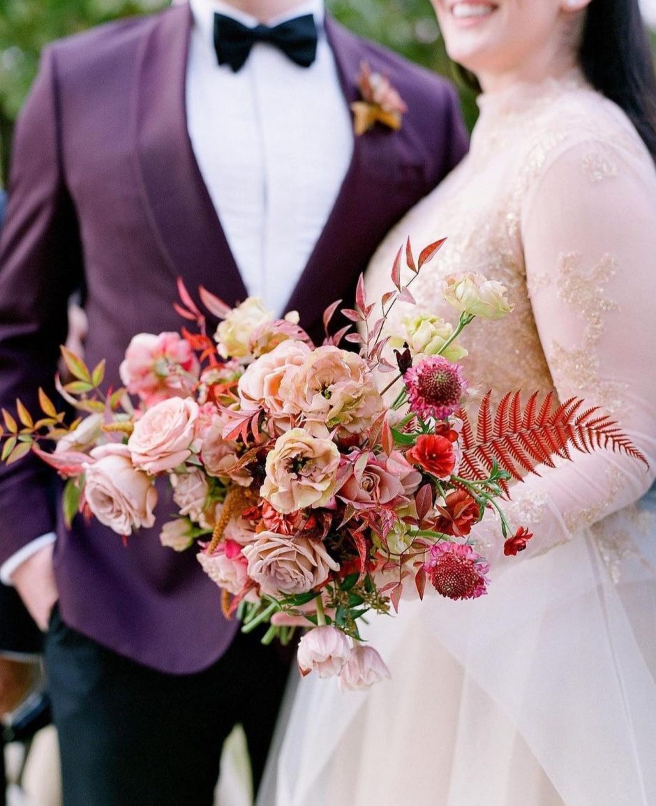 Bride holding bouquet of red and pink flowers.