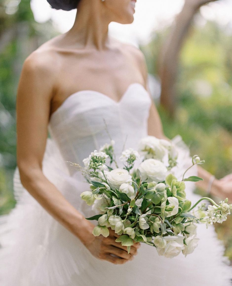 Bride holding wedding bouquet of white flowers.