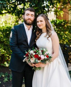 Newlywed couple with red Christmas flowers.