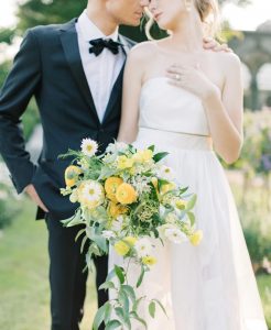 Bride with wedding bouquet of white daisies and yellow ranunculus.