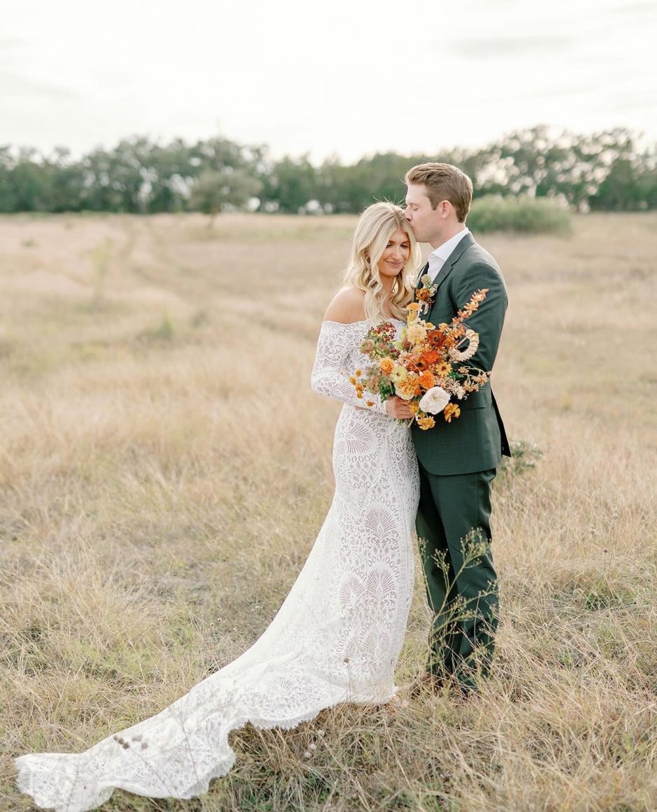Newlywed couple with bouquet of earth tone flowers.