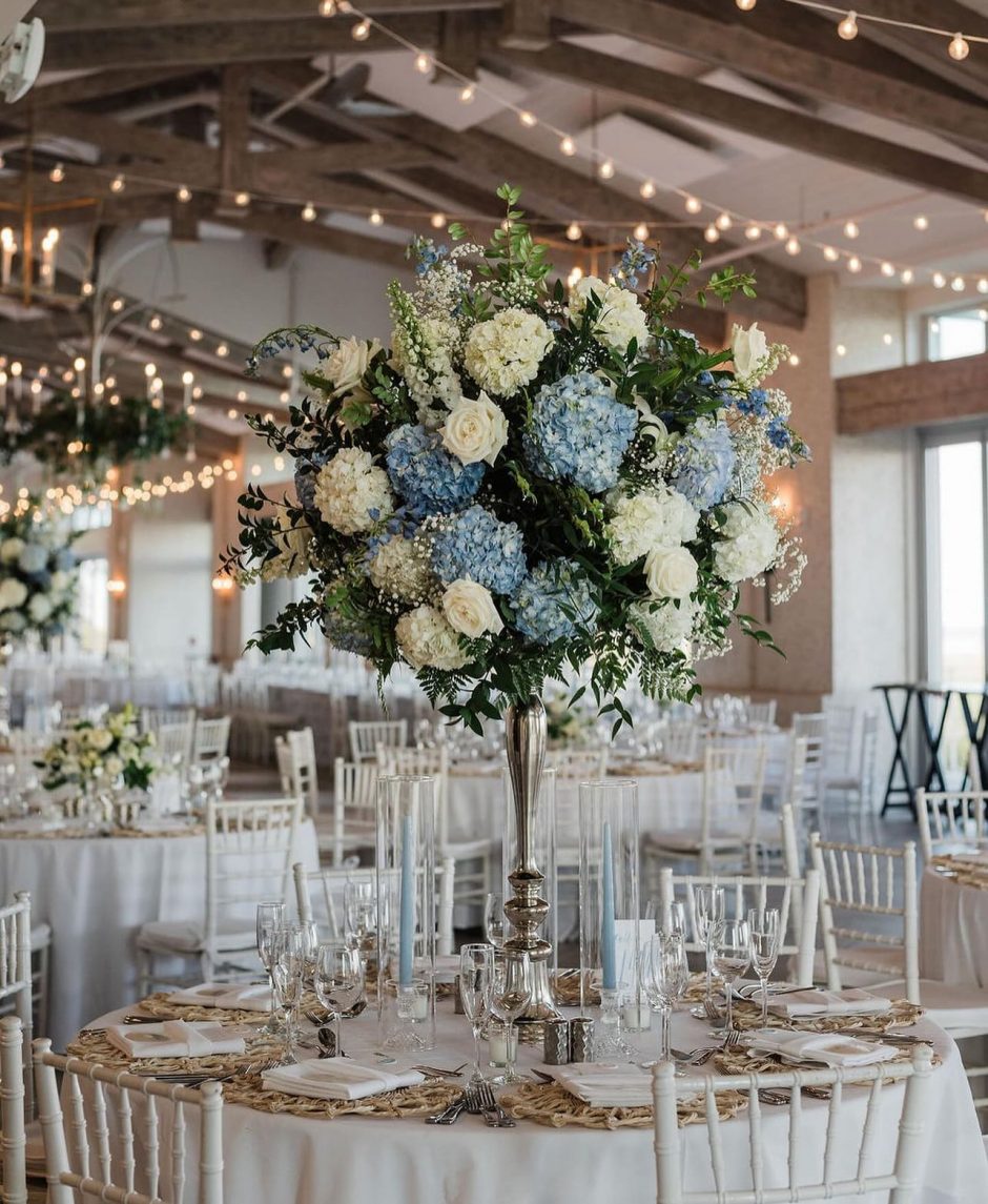 Wedding reception with white, blue, and green floral arrangements.