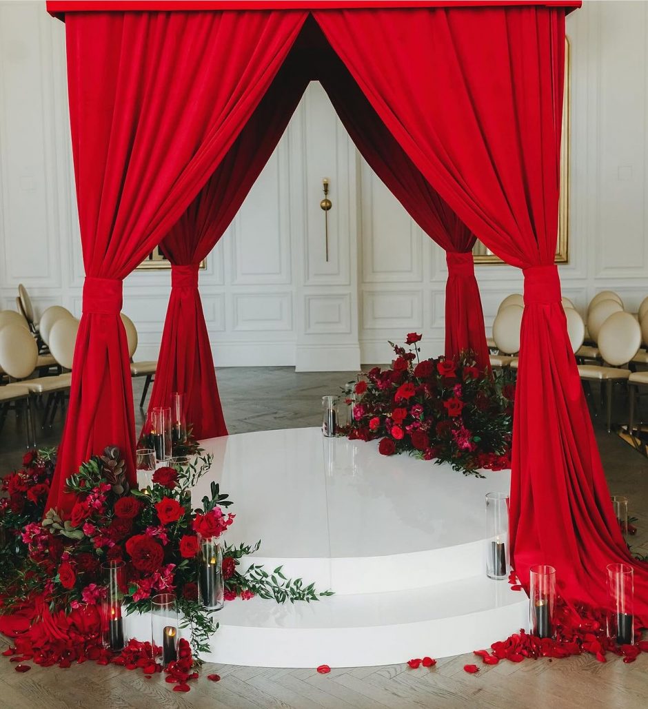 A wedding chuppah with red flowers.