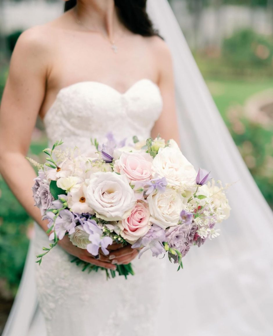 Bride holding bouquet with lavender, pink, and blush flowers.
