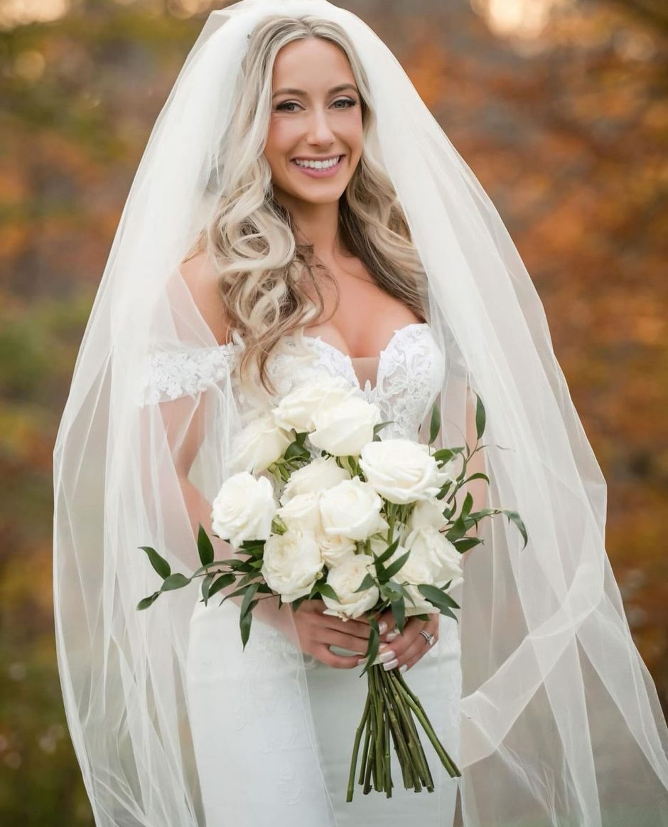 Bride holding wedding bouquet with white roses.