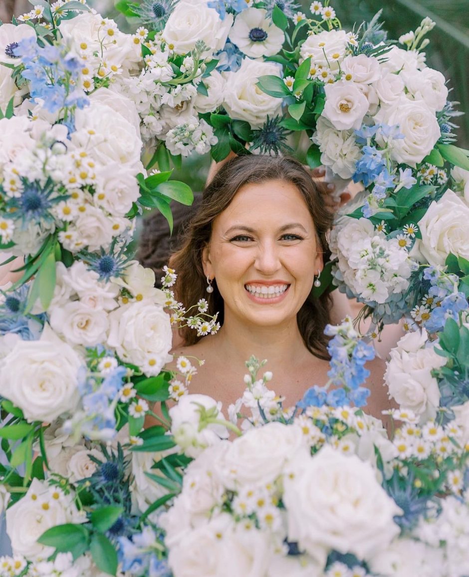 Bride surrounded by white and blue flowers.