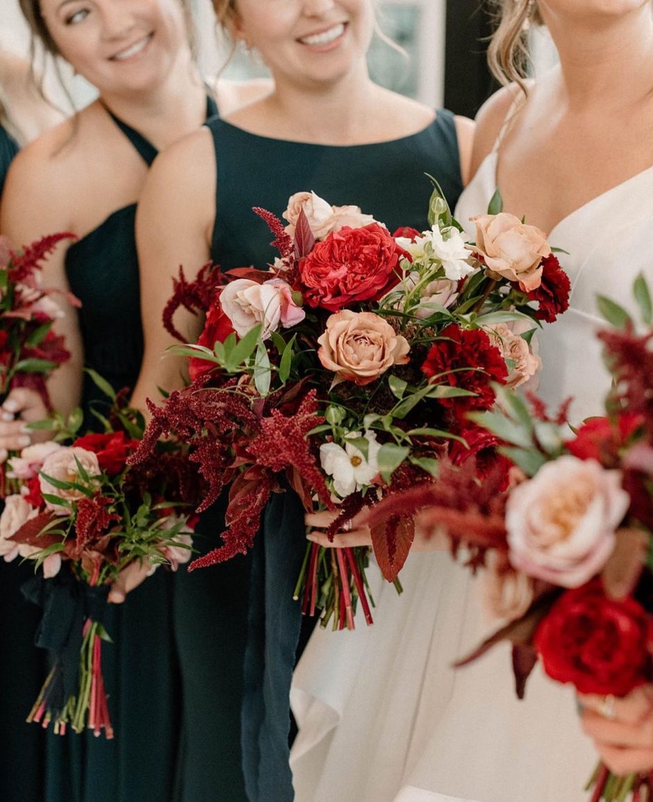 Bride and bridesmaids with pink, red, and burgundy flowers.