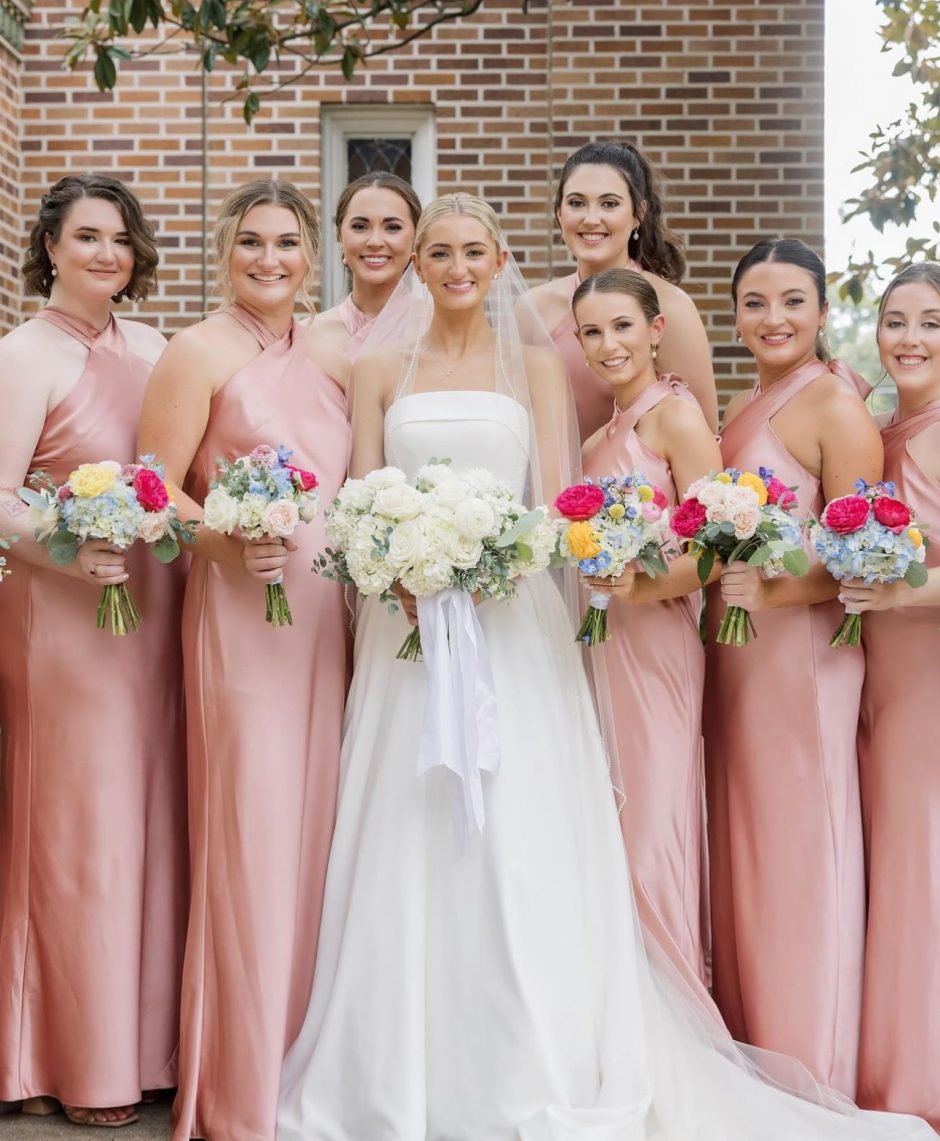 Bride with white wedding bouquet and bridesmaids with colorful bouquets.