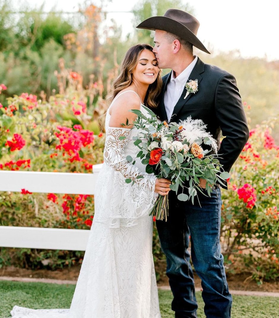 Newlywed couple with flowers for cowboy wedding theme.