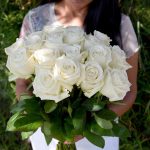 Woman holding bouquet of white roses.