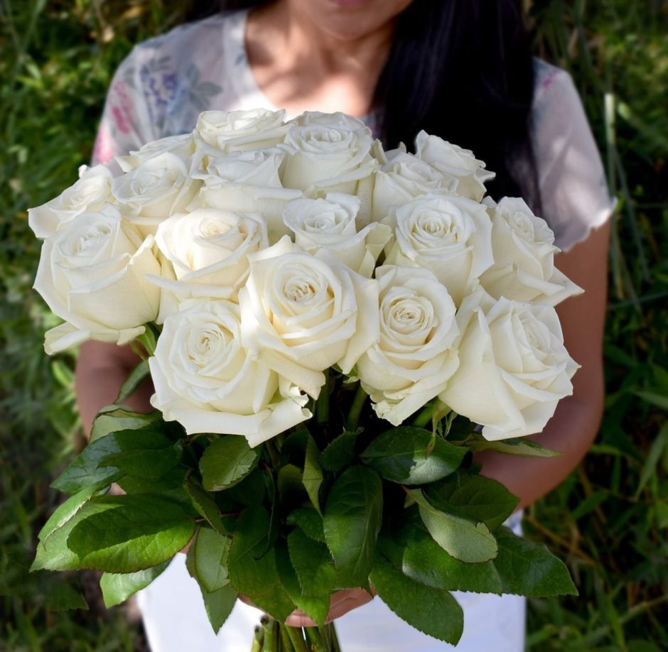 Woman holding bouquet of white roses.