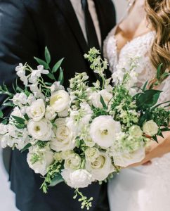 Bride holding bouquet of white ranunculus.