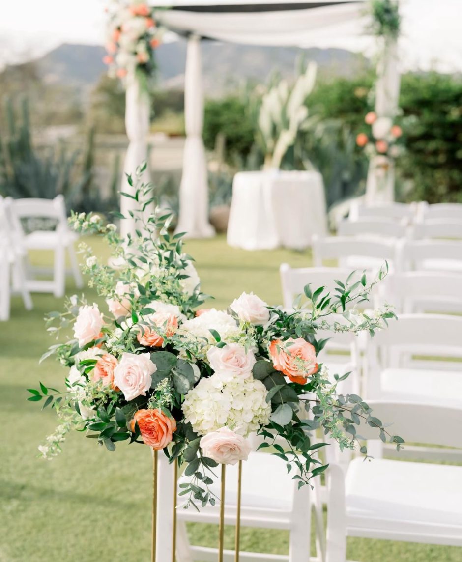 Outdoor wedding with coral roses and light green hydrangeas.