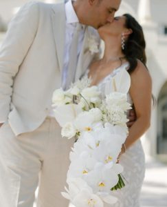 Newlywed couple with wedding bouquet of white anthuriums and white orchids.