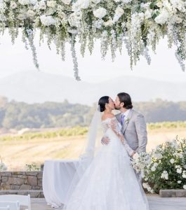 Newlywed couple embracing outdoors with beautiful flowers.