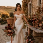 Latina bride in champagne wedding gown holding terracotta, rust, and burgundy fall bouquet at vineyard estate wedding.
