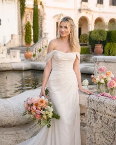 Blonde bride in ivory gown holding bouquet with garden roses and spray roses at a Mediterranean estate wedding.
