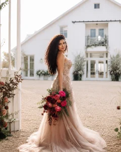 Colombian bride holding Attache hot pink roses with burgundy fall flowers and greenery outside Ivy Rose Barn.